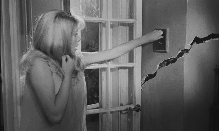 image noire et blanc d'une jeune femme craintive qui allume une lumière, image tirée du film Répulsion de Roman Polanski